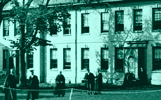 Exterior of the Huron College building with men out front in robes, photo from 1922