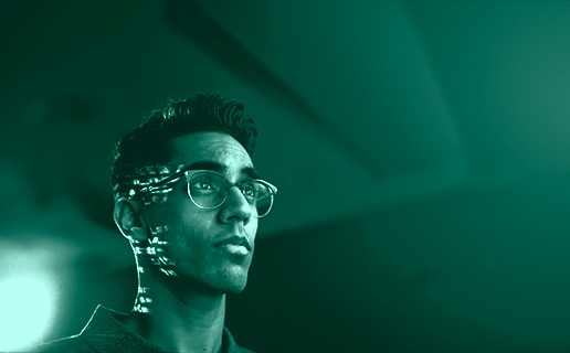 Portrait of student, young man looking into the distance, wearing eyeglasses, studio shot on dark background with digital lights on the student’s head, photo from 2019